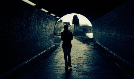 girl walking through the dark tunnel in townの写真素材
