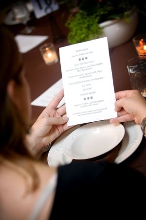 a woman reading from an organic menu during a catered wedding eventの写真素材