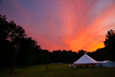 An event tent in a field at sunset during a weddingの写真素材
