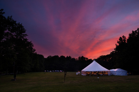 An event tent in a field at sunset during a weddingの写真素材