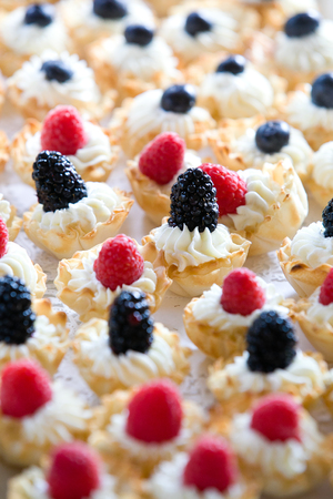 details of wedding treats with white cream and black berries and raspberriesの写真素材
