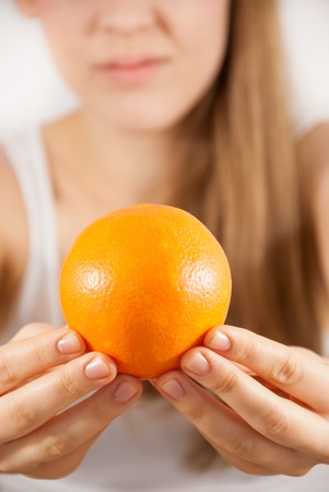 A young woman with an orangeの写真素材