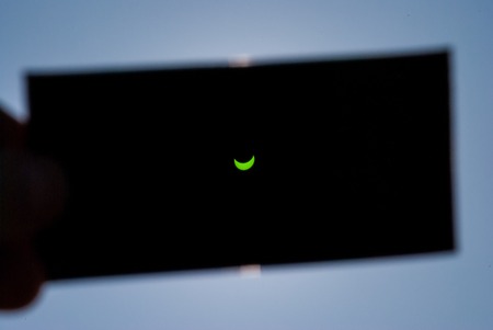 CRACOW, POLAND - MARCH 20, 2015: An observer watching a partial solar eclipse throught the dark...