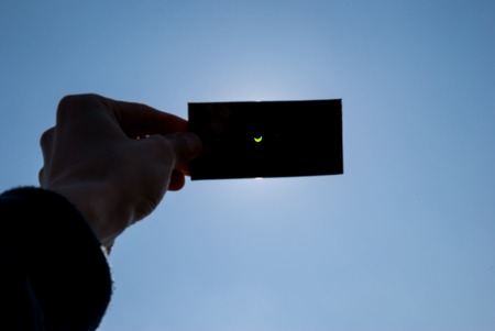 CRACOW, POLAND - MARCH 20, 2015: An observer watching a partial solar eclipse throught the dark...