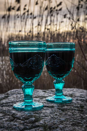 red wine glasses on a lake at sunset time