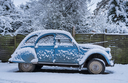 Old classic car in a snowy, rural landscape.の写真素材