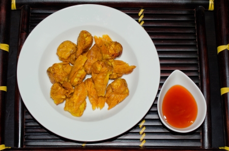 A dish of fried wonton with sweet chillii sauce on bamboo tray, dark isolated background.の写真素材