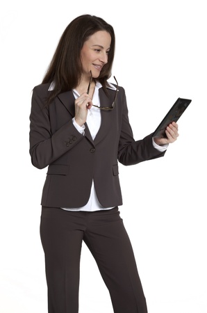 Attractive businesswoman holding and looking at tablet device against white background.の写真素材