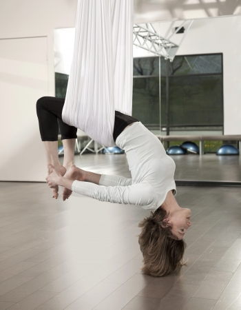 Woman doing anti gravity yoga exercise in fitness centre.の写真素材