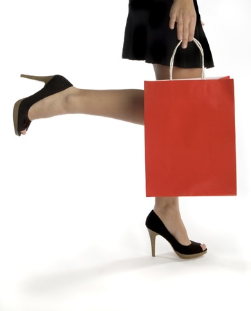 Waist-down view of woman carrying red shopping bagの写真素材