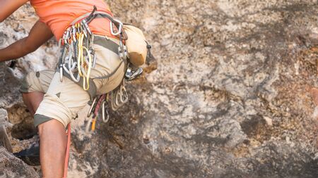 a man with red shirt climbing on the cliff with equipmentの写真素材
