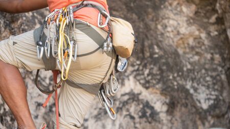 a man with red shirt climbing on the cliff with equipmentの写真素材