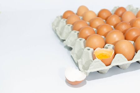 A lot of eggs put on tray on white background and one of these was brokeの写真素材