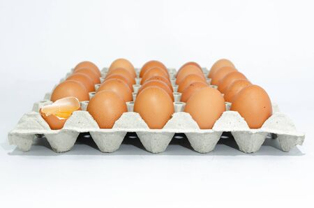 A lot of eggs put on tray on white background and one of these was brokeの写真素材