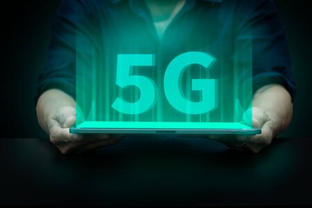 glowing 5G font show on tablet screen, technology concept