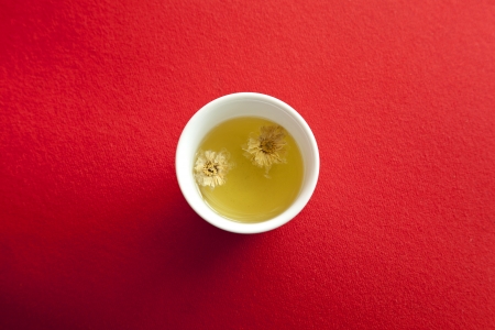 a cup of warm Chrysanthemum tea on red fabric backgroundの写真素材