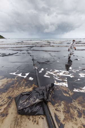 RAYONG, THAILAND - JULY 31, 2013  A worker in biohazard suit during the clean-up operation from crude oil spilled into Ao Prao Beach on July 31, 2013 in Rayong province, Thailand のeditorial素材