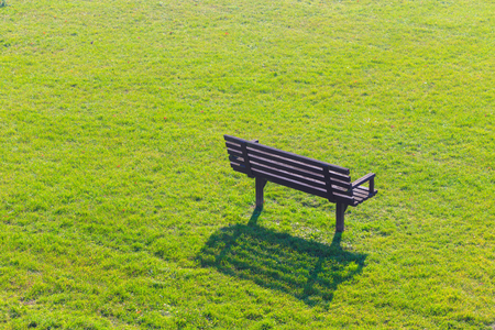 Wooden bench in green grass lawn field park.の写真素材