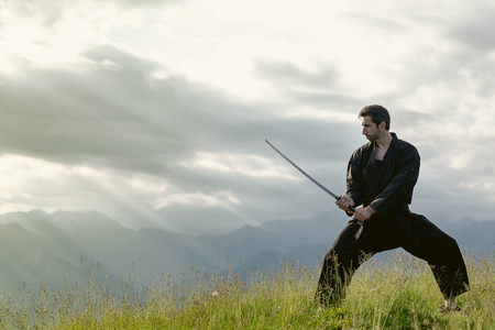 Wushu master with sword, meditation on mountainの写真素材
