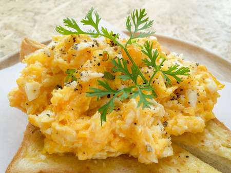 Scrambled eggs on bread toast and coriander on top.