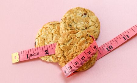 Weight loss cereal cookies that have a tape wrapped around on a pink background