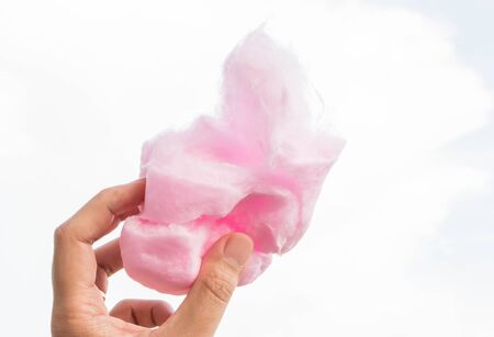 male hand holding cotton candy on blue sky backgroundの写真素材