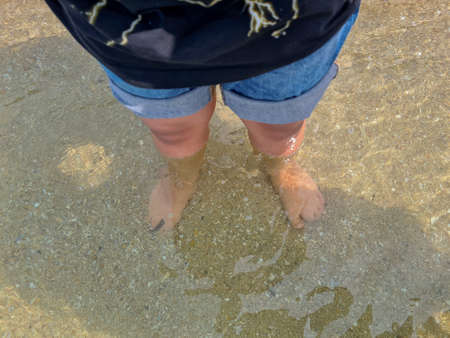 Boy feet barefoot stand on the sand of the beachの写真素材
