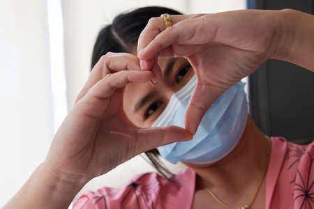 Woman's hand making a heart-shaped symbol.