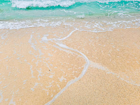 Blue water, waves crashing on the shore causing air bubbles.
