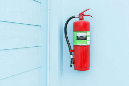The fire extinguisher installed on the blue wall of the house.