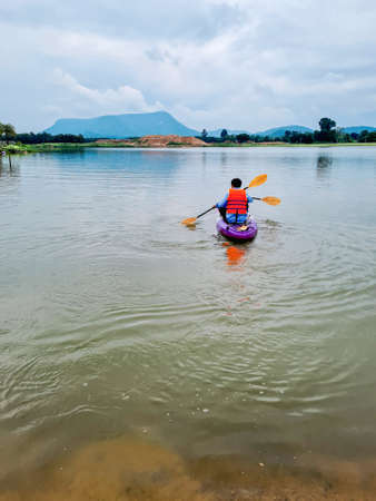 A father and son duo paddles in a canoe during the setting sun. cloudy sky compositeの写真素材