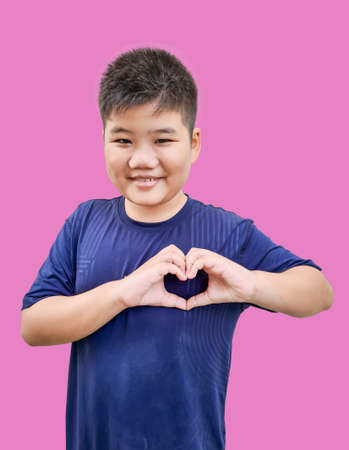 Portrait of happy boy with heart shape isolated on pink background.