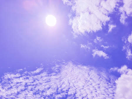 The sun shone on the purplish blue sky and the white clouds.の写真素材