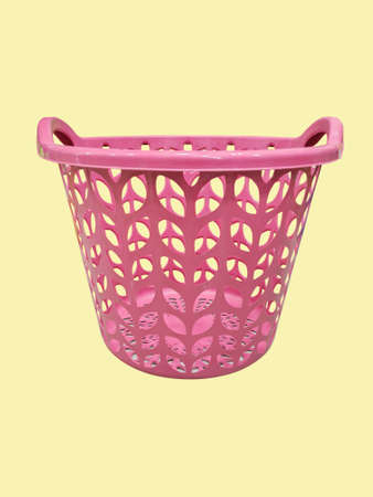 Side view of pink round plastic basket isolated on yellow background.の写真素材