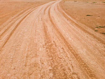 the rural not asphalted road passing through an agricultural field.arid red soil pathの写真素材
