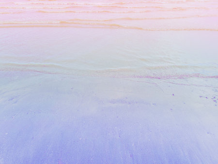 The foamy clear sea waves roll on the pink sandy beach and the turquoise water.の写真素材
