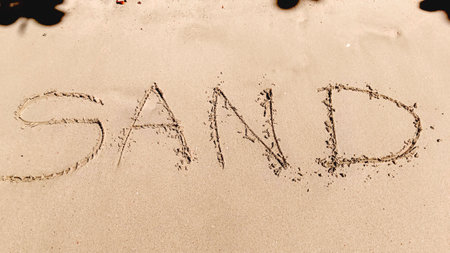 Hand writing text on sandy background with sunlight.の写真素材