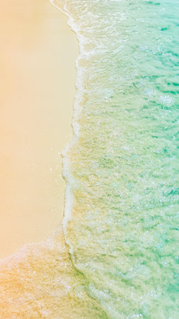 Soft blue ocean wave on clean sandy beach, vertical
