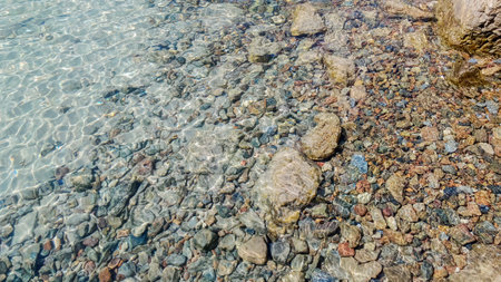 Shiny sea water with sparkles, pebbles seabed, crystal clear rippled water. Circles on the water. Relax, zen, meditation.の写真素材