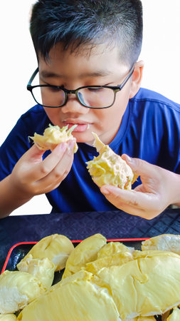 Asian boy eating durian fruit in isolated white backgroundの写真素材