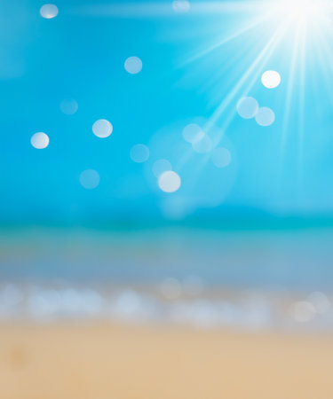 Natural blurred defocused background for concept summer vacation. Nature of tropical summer beach with rays of sunlight. Light sand beach, ocean water sparkles against blue sky.の素材