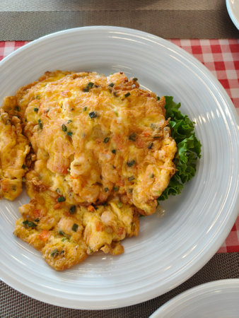 Shrimp omelet rice on a white plate looks delicious.