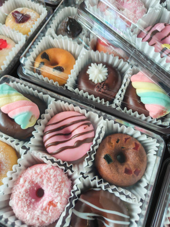 A delightful assortment of donuts, each adorned with colorful sprinkles, creamy frosting, and tempting chocolate glazeの写真素材