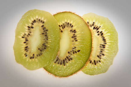 Kiwi section slices photographed in a studio with a light form under the sliceの写真素材