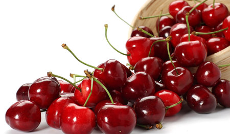 Cherries in a wooden bowl on a white background close-upの素材