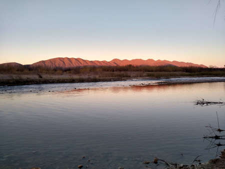 Sunset over the river in the desert with mountains in the background