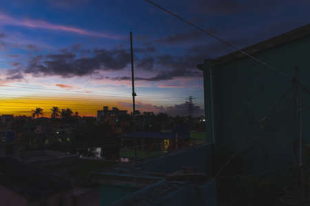 A beautiful sunset colorful sky blue and violet with clouds and village at distance