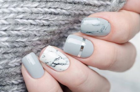 white grey marble manicure with silver stripe on grey backgroundの写真素材