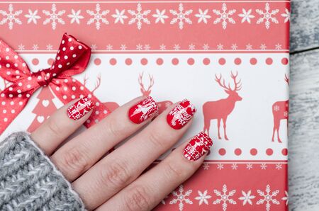 red Christmas manicure with deer and snowflakes and Norwegian pattern with box for giftsの写真素材