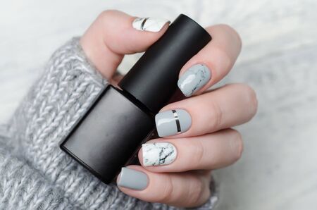 white and grey marble manicure with silver stripe on grey backgroundの写真素材